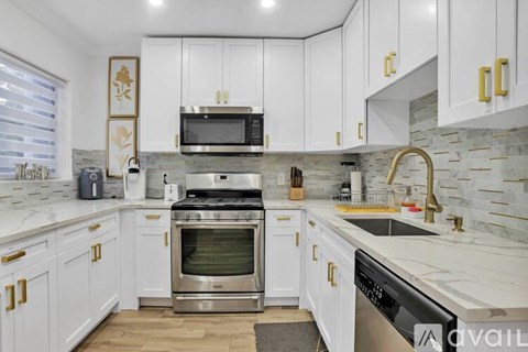 A kitchen with white cabinets and a marble countertop.