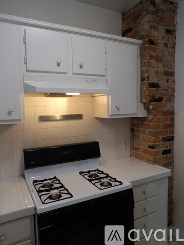 A kitchen with white cabinets and a black stove top.