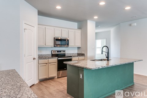 A kitchen with a green island and white cabinets.