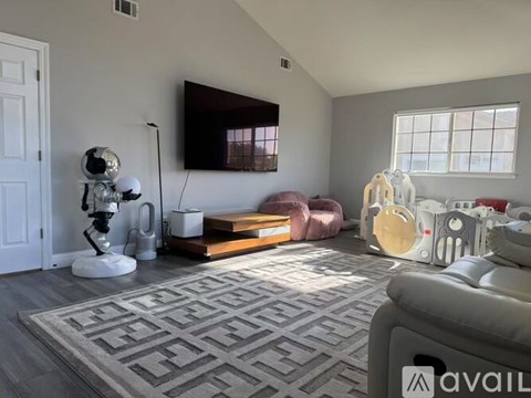 A living room with a grey sofa and a white robot.