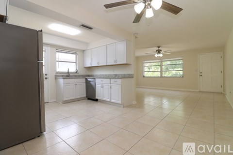 A kitchen with white cabinets and a black refrigerator.