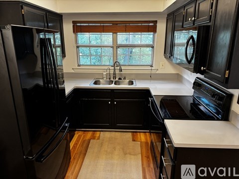 A kitchen with black cabinets and a wooden floor.