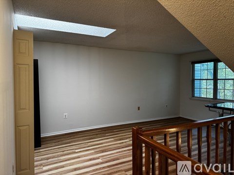 A room with wooden flooring and a window with a view of trees.