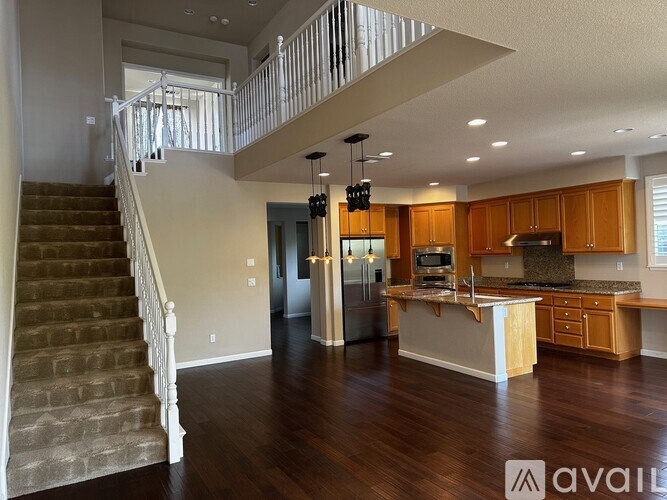 A spacious kitchen and living room with a staircase leading to the upper floor.