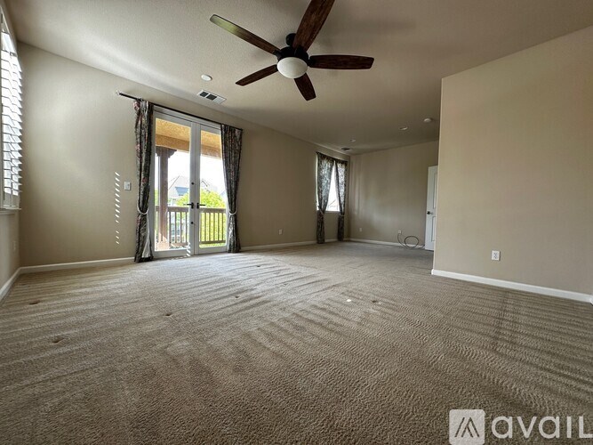 A spacious room with a ceiling fan and carpeted floor.