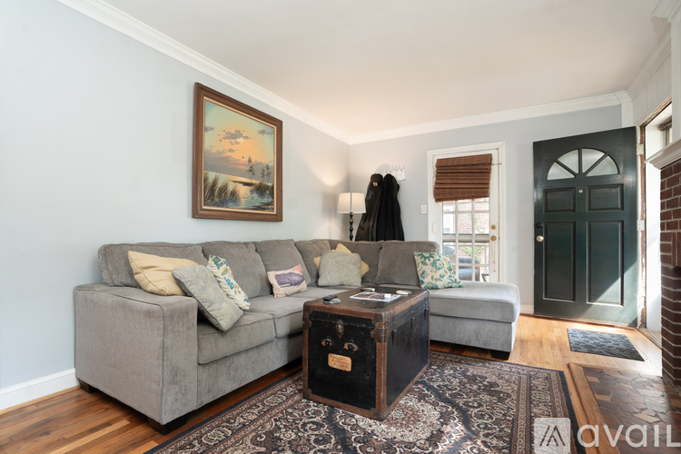 A living room with a grey couch, a coffee table, and a painting on the wall.
