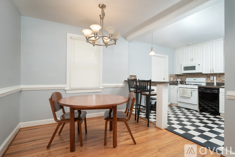 A kitchen with a table and chairs in the foreground and a checkered floor.
