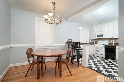 A kitchen with a table and chairs in the foreground and a checkered floor.
