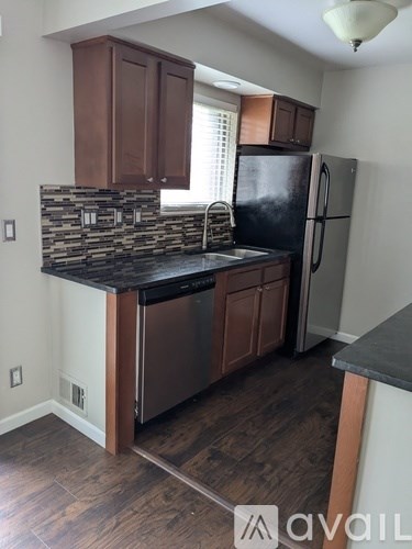 A kitchen with wooden cabinets and a black fridge.