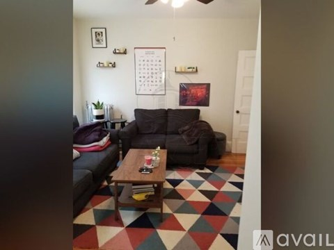 A living room with a black couch and a wooden coffee table.