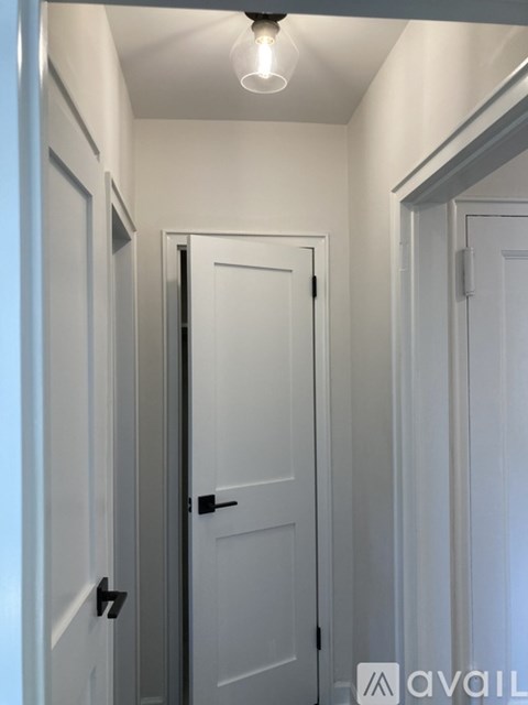 A white door with a black handle is in the middle of a hallway.