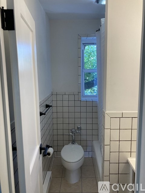 A white toilet in a small bathroom with a window.