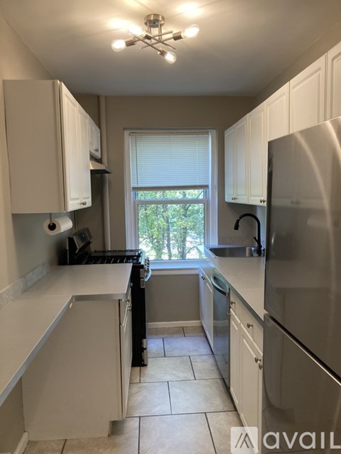 A kitchen with white cabinets and a stainless steel refrigerator.