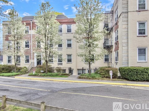 A street view of a residential area with apartment buildings and trees.