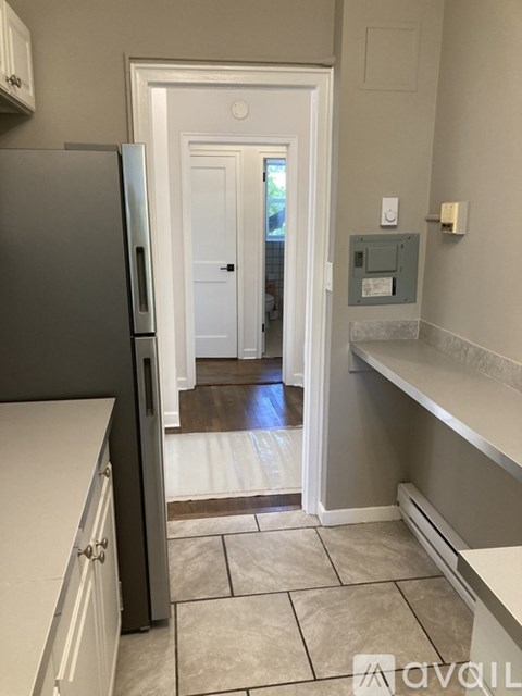 A kitchen with a refrigerator and a doorway leading to a hallway.