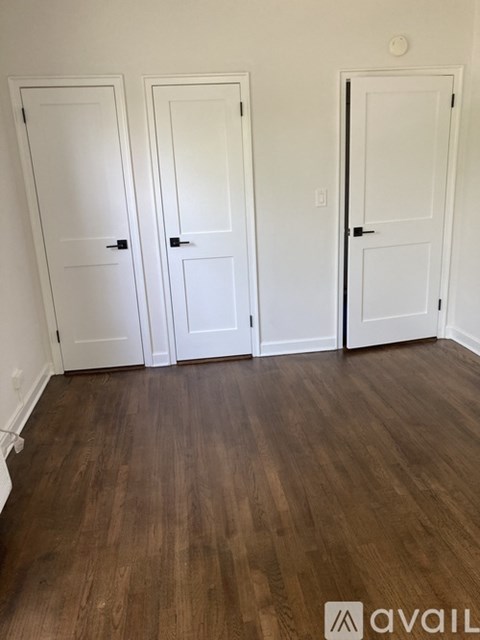 Three white doors in a room with wooden floors.