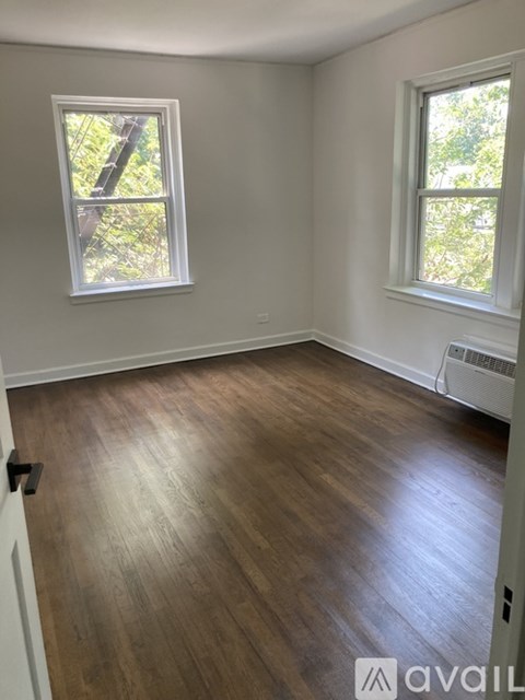 A room with wooden floors and two windows.