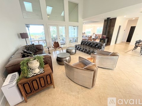 A living room with a couch, chair, ottoman, and a table with a plant on it.