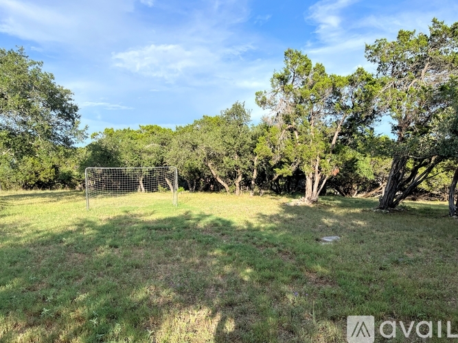 A soccer goal stands in the middle of a grassy field with trees in the background.