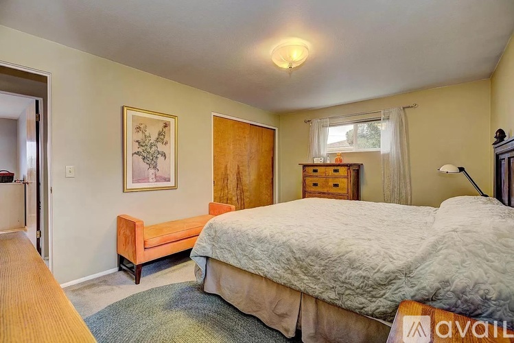 A bedroom with a bed, dresser, and window.
