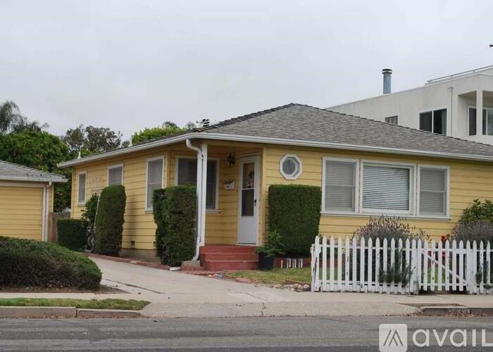 A yellow house with a white picket fence in front.