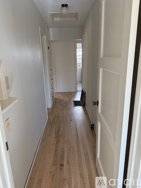 A long hallway with white walls and wood floors.