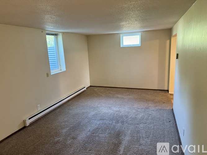 A room with a carpeted floor, a window with blinds, and a door.