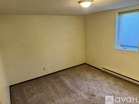 A room with a carpeted floor and a window with blinds.