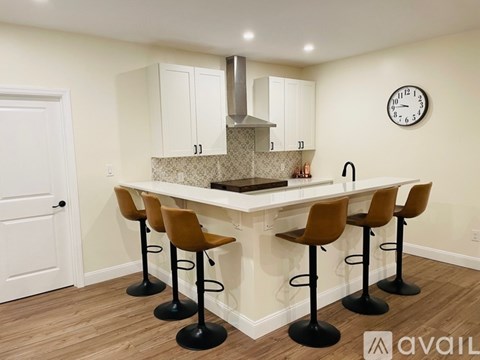 A kitchen with a bar area featuring a white counter and brown barstools.