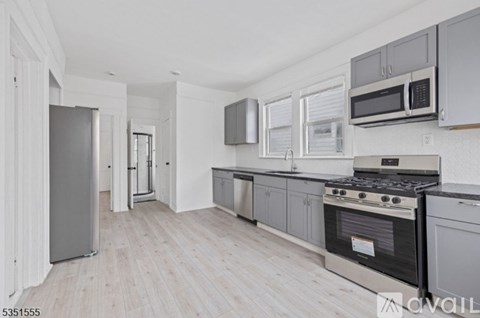 A kitchen with a black stove top oven and a refrigerator with a white door.