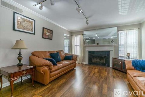 A living room with a brown leather couch and a fireplace.