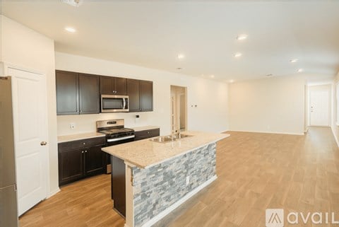 A modern kitchen with dark brown cabinets and a stone counter.