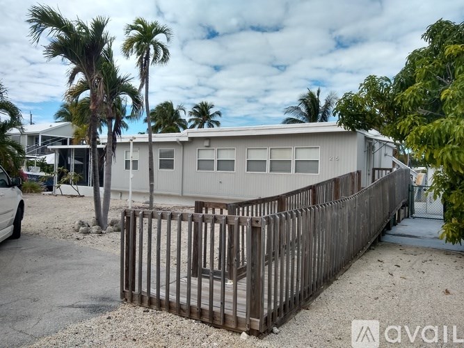 A house with a wooden fence in front of it is for sale.