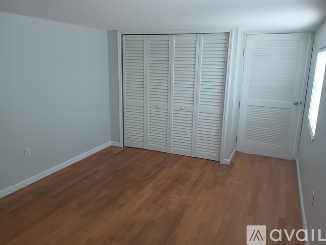 A room with wooden flooring and white closet doors.