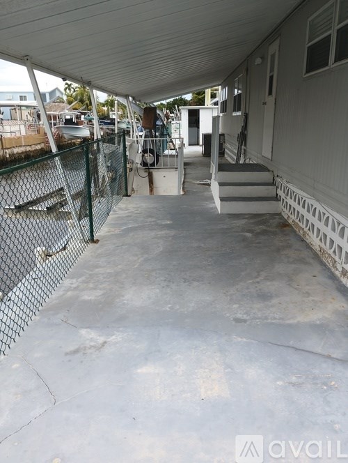 A concrete patio with a white fence and a white house in the background.