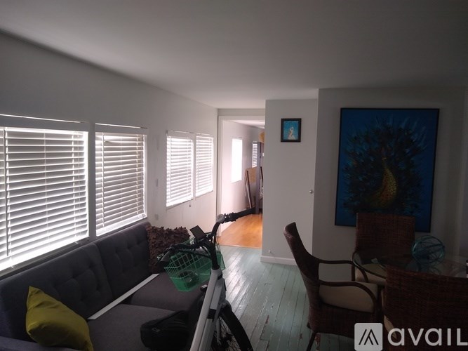 A living room with a grey couch and a painting on the wall.