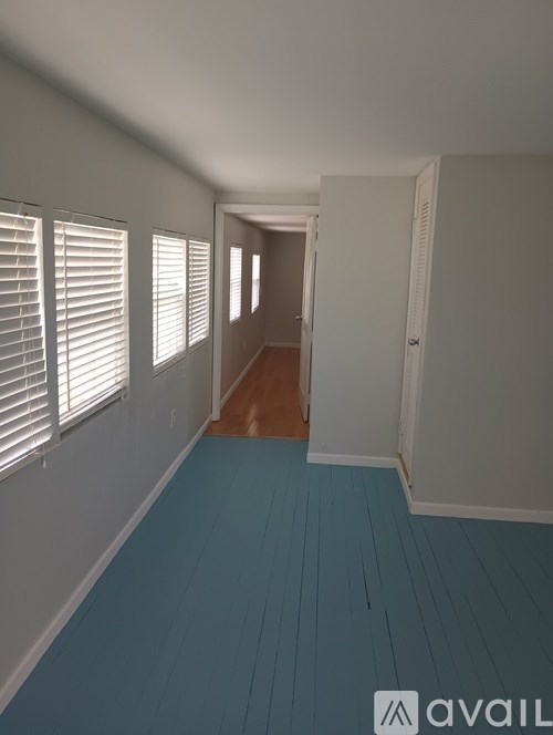 A hallway with white walls and blue flooring.