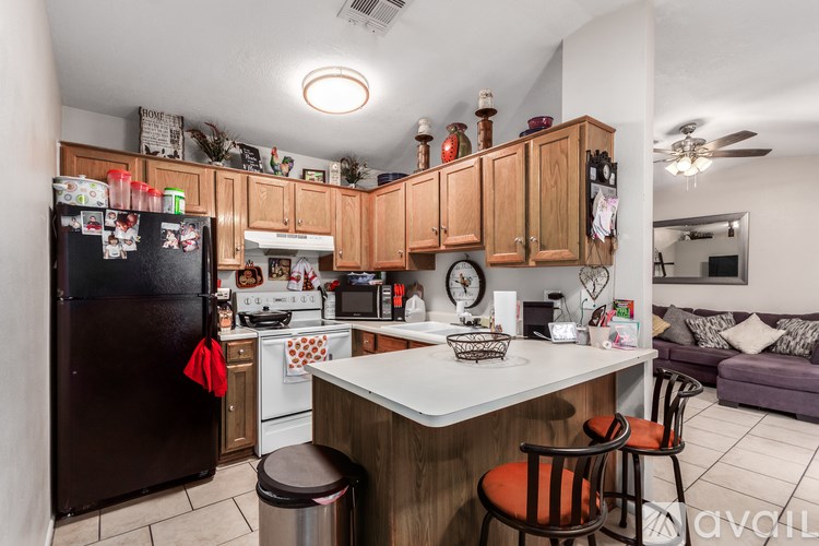 A kitchen with a black fridge and wooden cabinets.