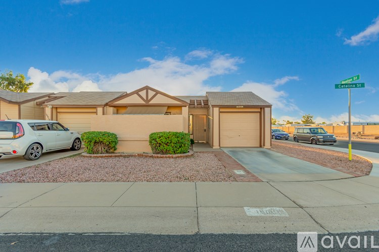 A house with a car parked in front and a street sign on the corner.