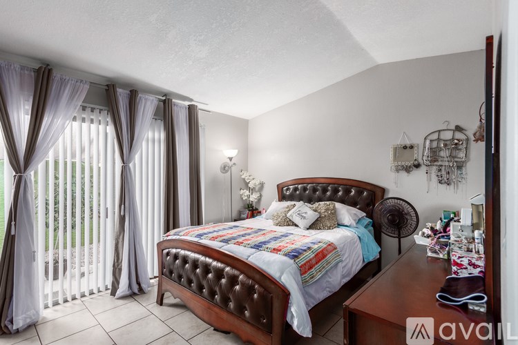 A bedroom with a bed, nightstand, and window with curtains.