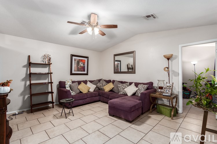 A living room with a purple couch and a fan on the ceiling.