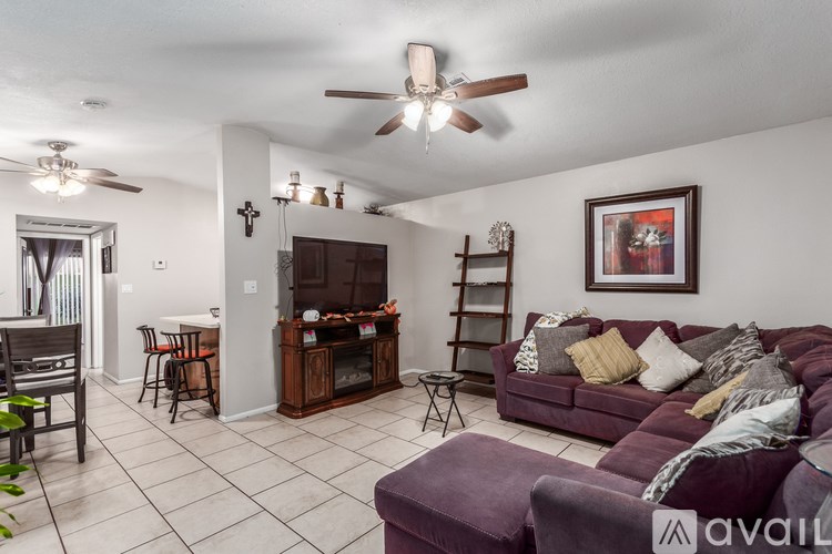 A living room with a purple couch and a fan on the ceiling.