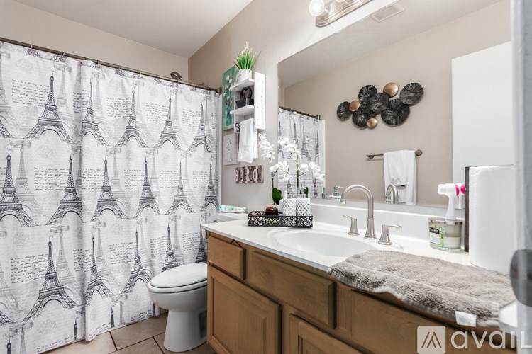 A bathroom with a toilet, sink, and shower curtain with an Eiffel Tower pattern.