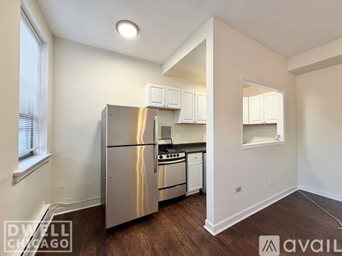 A kitchen with white cabinets and a stainless steel refrigerator.