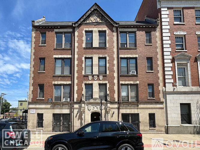 A black SUV is parked in front of a red brick building.