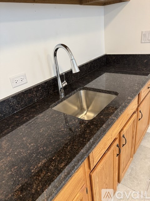 A kitchen sink with a chrome faucet on a granite countertop.