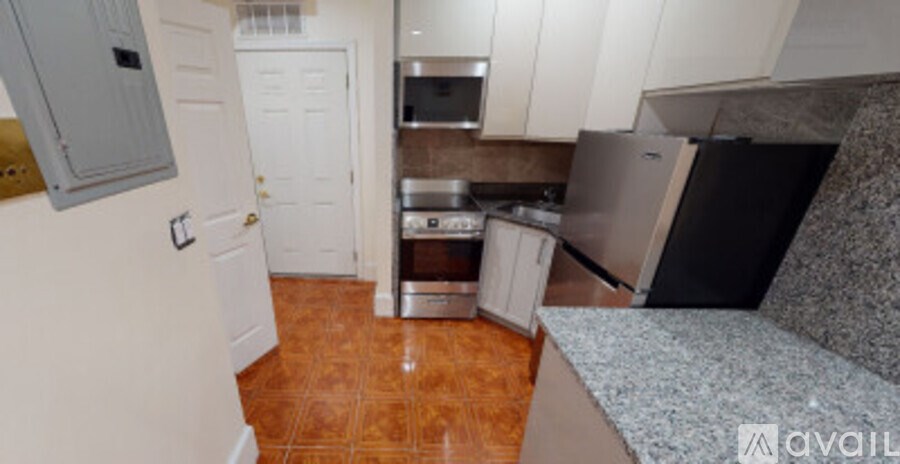 A kitchen with white cabinets and a black fridge.