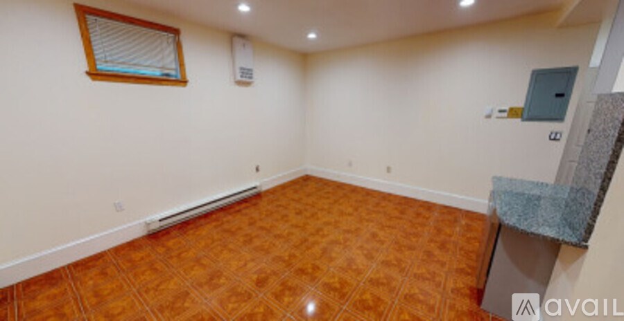 A room with a brown floor and a window with blinds.