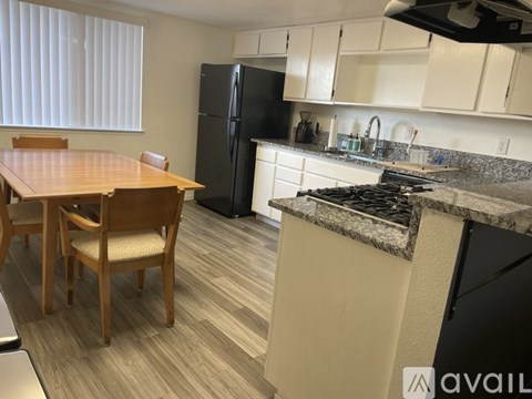 A kitchen with a table and chairs in front of a refrigerator.