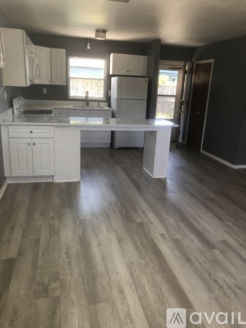 A kitchen with white cabinets and a wooden floor.